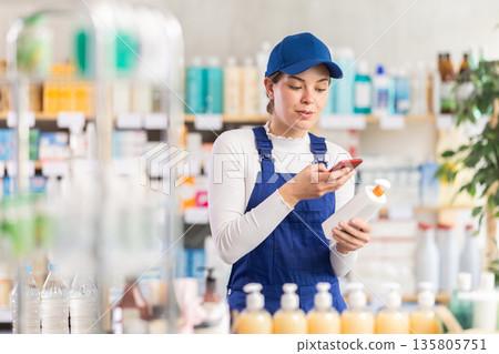 Young woman worker scanning qr code of cream Young woman worker scanning qr code of cream 135805751