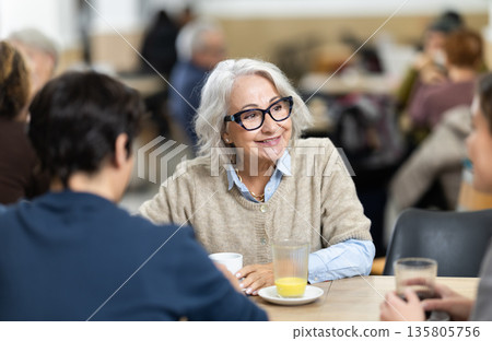 Large family is having breakfast in a cozy cafe, discussing news. 135805756