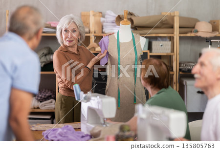 Female teacher demonstrating sleeve placement on dress form to elderly students Female teacher demonstrating sleeve placement on dress form to elderly students 135805763