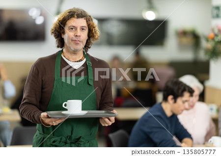 Friendly cafe male employee invites you to visit establishment Friendly cafe male employee invites you to visit establishment 135805777