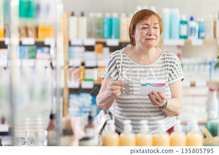 Ederly woman in summer clothes looking for medicine in pharmacy 135805795