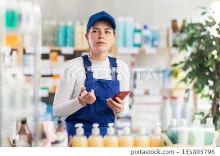 Builder woman looking at shop windows in pharmacy with phone 135805796