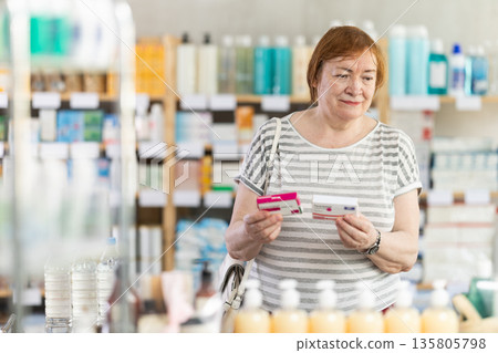 In sales area of pharmacy, mature woman examines packaging of paracetamol pill In sales area of pharmacy, mature woman examines packaging of paracetamol pill 135805798