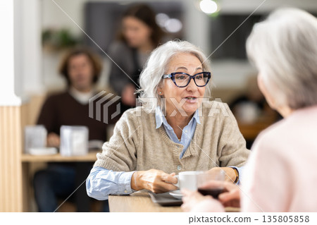 Elderly women in cafe has nice conversation and discusses news of day Elderly women in cafe has nice conversation and discusses news of day 135805858
