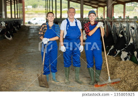 Man and two women working in cowshed 135805925