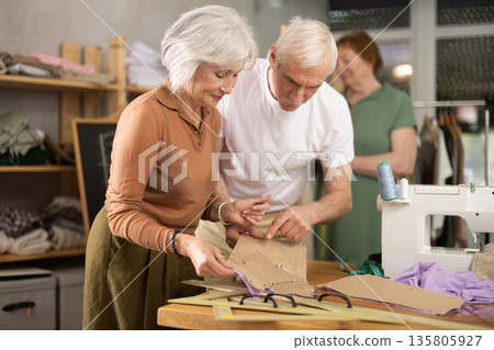 Elderly man and woman working with mannequin and making pattern in class Elderly man and woman working with mannequin and making pattern in class 135805927