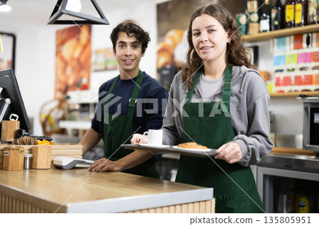 Barista girl presenting coffee and croissant, give out order, guy in background Barista girl presenting coffee and croissant, give out order, guy in background 135805951