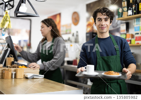 Cafe waiter carries tray with croissant and coffee 135805982
