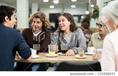 Positive family talking cheerfully and drinking wine at table in cafe 135806031