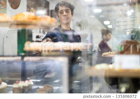 Waiter guy laying out desserts on the counter Waiter guy laying out desserts on the counter 135806072