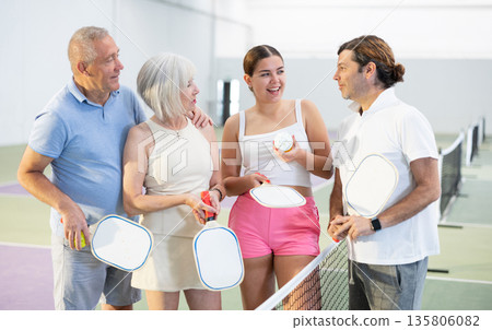 Group of smiling pickleball players talking on indoor court 135806082