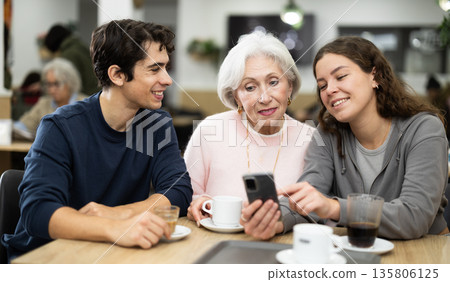 Large friendly family gathered at table to have meeting in restaurant 135806125
