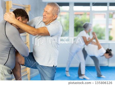 Old man practicing self-defense techniques in pairs Old man practicing self-defense techniques in pairs 135806126