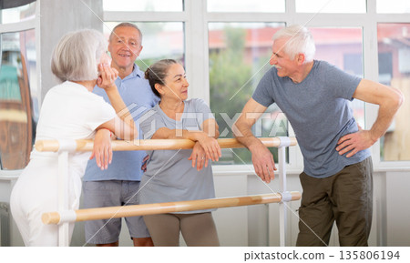 Elderly ballet lovers communicate with each other during break between classes in choreographic studio Elderly ballet lovers communicate with each other during break between classes in choreographic studio 135806194