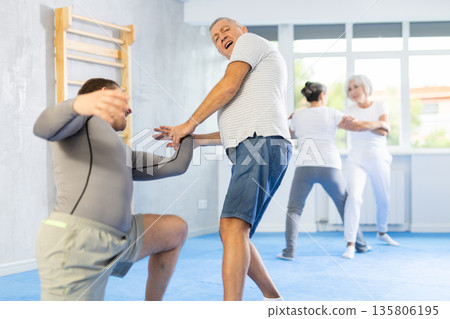 Old man twisting her opponent's arm during self-defense classes Old man twisting her opponent's arm during self-defense classes 135806195