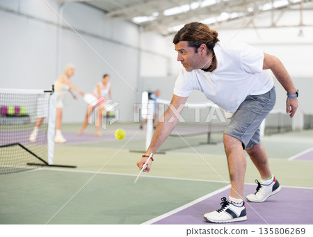 Concentrated adult pickleball player preparing to return ball Concentrated adult pickleball player preparing to return ball 135806269