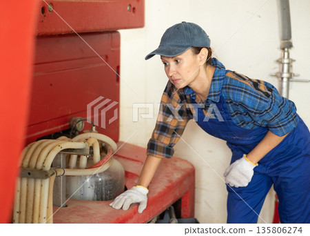 Adult woman near automatic milking machine 135806274
