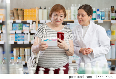 pharmacist helps a woman scan a barcode pharmacist helps a woman scan a barcode 135806280
