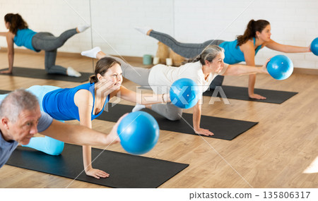 Group exercising with pilates balls during workout in fitness studio Group exercising with pilates balls during workout in fitness studio 135806317