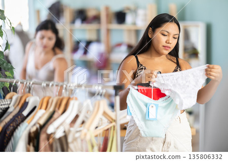 Female shopper selects panties in fashionable clothing boutique 135806332
