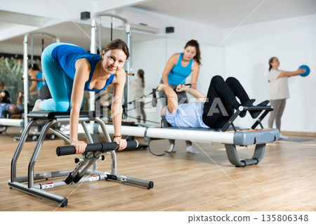 Young woman practicing pilates exercises on combo chair 135806348