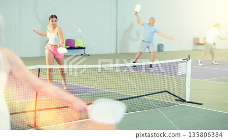 Pickleball game - people actively kicks the ball during pickleball game 135806384