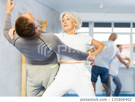 Old woman practicing self-defense techniques in pairs 135806402