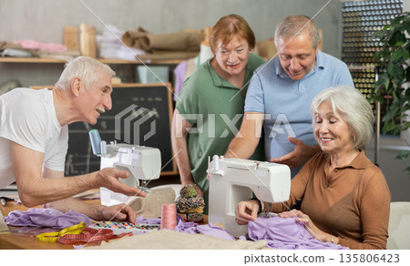 Senior female teacher demonstrates technique sewing with machine, shares skills with elderly students Senior female teacher demonstrates technique sewing with machine, shares skills with elderly students 135806423