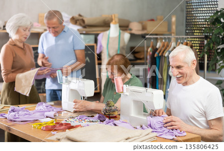 Some people communicate and discuss pattern, while others sew using sewing machine at lesson Some people communicate and discuss pattern, while others sew using sewing machine at lesson 135806425