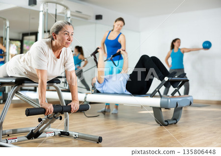Elderly woman doing stretching exercises on pilates chair 135806448