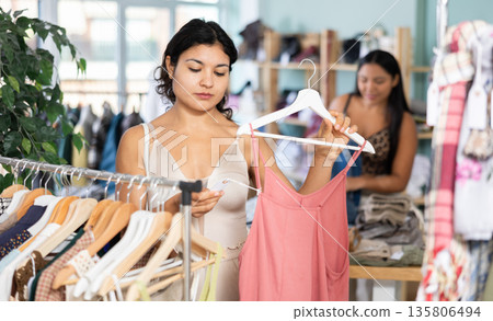 Latina woman chooses summer clothes, tops and dresses with interest 135806494