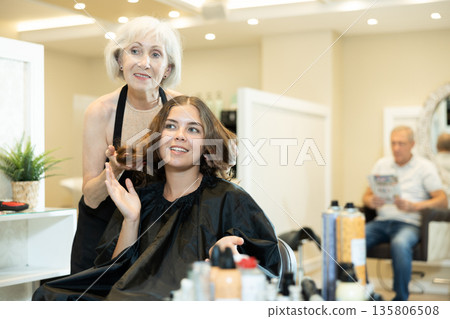 Elderly woman hairdresser master does discusses with client length of hair, shape of haircut Elderly woman hairdresser master does discusses with client length of hair, shape of haircut 135806508