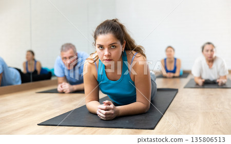 Class of male and women of different ages standing in plank on elbows during Pilates training together in gym 135806513