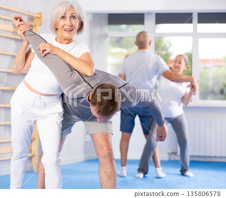 Old woman twisting her opponent's arm during self-defense classes 135806578