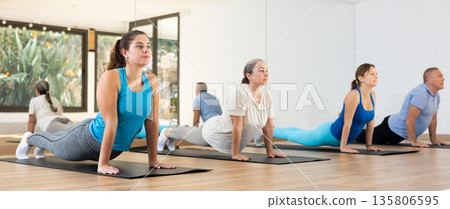Girl doing Upward Facing Dog pose during group yoga workout 135806595