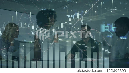 Presenting woman in blazer leading meeting at office glass table, with laptops and financial charts 135806893