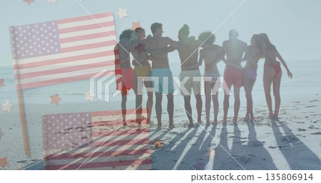 Linking arms eight friends wearing swimwear standing on beach, with American flag overlay and stars 135806914