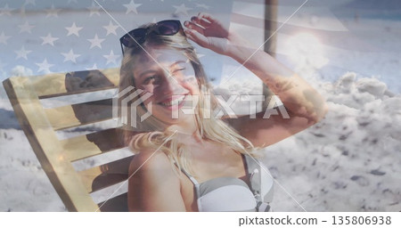 Reclining woman in bikini adjusting sunglasses on lounge chair at beach, with American flag overlay Reclining woman in bikini adjusting sunglasses on lounge chair at beach, with American flag overlay 135806938