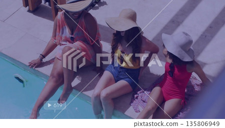 Sitting three women dipping legs into turquoise pool on poolside deck, with sun hats and towel Sitting three women dipping legs into turquoise pool on poolside deck, with sun hats and towel 135806949