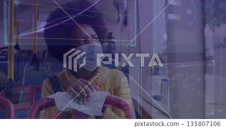 Woman wearing yellow sweater and mask gripping seat top in bus, with digital overlay on window 135807106