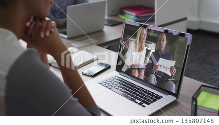Woman grey top watching laptop showing presenters holding charts at office, phone notebook binders 135807148