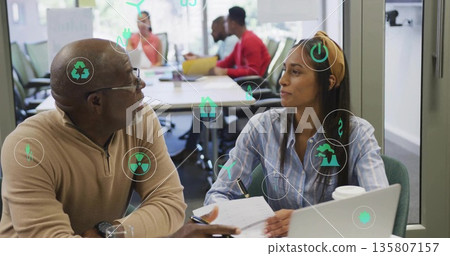 Senior colleague and coworker discussing ideas in meeting room, with notebook and digital icons Senior colleague and coworker discussing ideas in meeting room, with notebook and digital icons 135807157