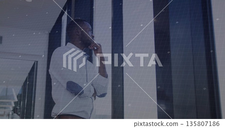 Gazing businessman wearing casual shirt leaning inside corridor, with glass panels and grid overlay Gazing businessman wearing casual shirt leaning inside corridor, with glass panels and grid overlay 135807186