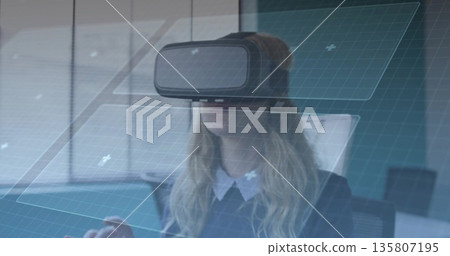 Navigating professional wearing blazer using VR headset at desk, with floating UI panels 135807195
