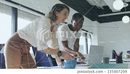 Leaning two women wearing business attire collaborating on laptop at desk with chart overlay Leaning two women wearing business attire collaborating on laptop at desk with chart overlay 135807209