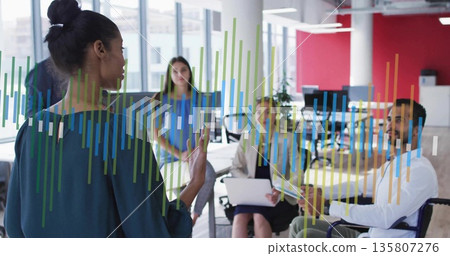 Presenting woman in green blouse gesturing at charts in office, with laptop wheelchair, copy space Presenting woman in green blouse gesturing at charts in office, with laptop wheelchair, copy space 135807276