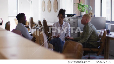 Female coworker wearing white shirt and jeans leading discussion in coworking space, with laptop Female coworker wearing white shirt and jeans leading discussion in coworking space, with laptop 135807300