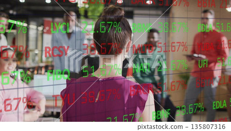 Presenting woman in purple blouse demonstrating codes on glass board in open office with laptops 135807316