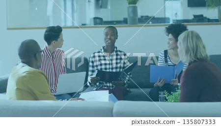Team of colleagues planning and reviewing project details in office lounge, with laptops folders Team of colleagues planning and reviewing project details in office lounge, with laptops folders 135807333