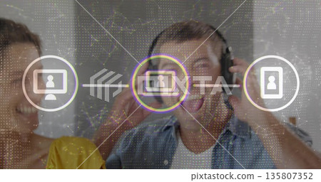 Adjusting over-ear headphones man singing at studio with woman in yellow top, digital network icons 135807352